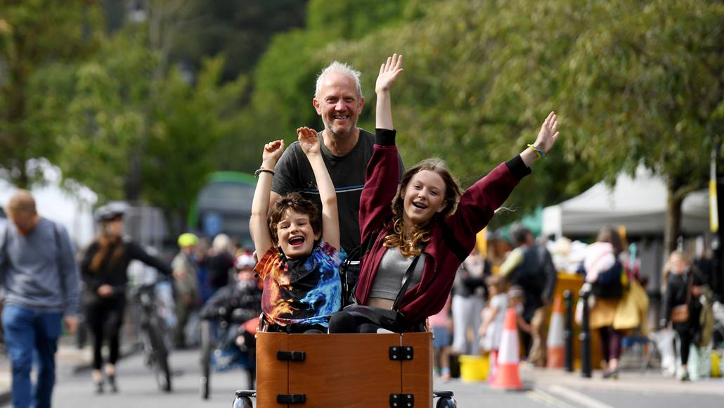 A man riding a cargo bike with two children