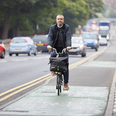 Man on folding bike on cycle route next to road