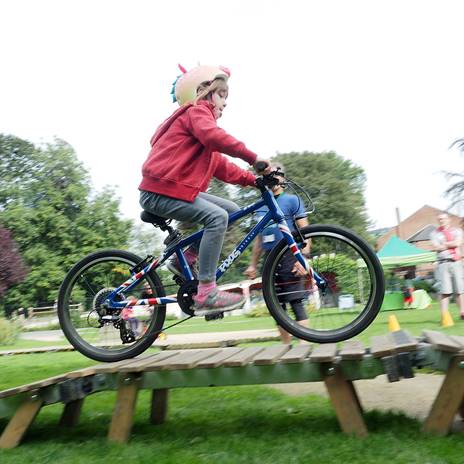 Child in helmet cycling on wooden ramp