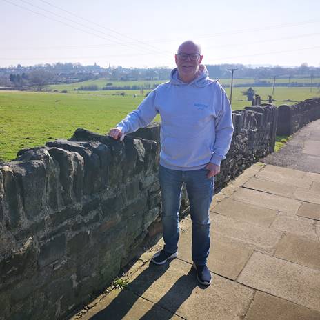 Mick Scholey standing by a dry stone wall